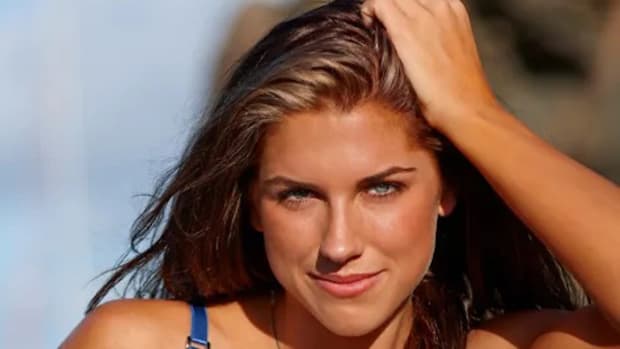 Alez Morgan poses in a blue bikini with her head leaning against her hand.